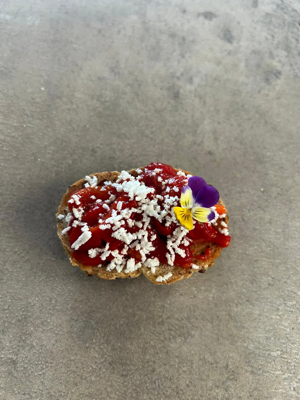 Bruschetta tomate confit, chèvre émietté et pensée comestible